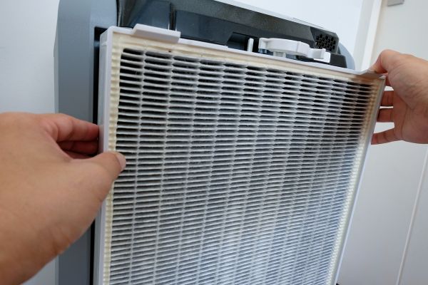 An HVAC technician replaces a filter on an air cleaner