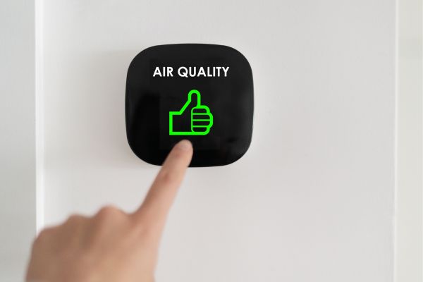 A finger pushes a button on an air purifier